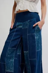 Pantalón flare de tiro alto, color azul, con diseño de patchwork y costuras visibles en contraste. Presenta perneras anchas de corte fluido.