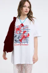 Remera de corte oversized en color blanco, con cuello redondo y mangas cortas. Presenta una estampa central con la frase 'Living a hot life' y un diseño de ajíes rojos.