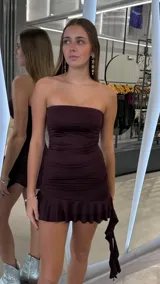 Vestido corto bordó estilo strapless con fruncidos en el cuerpo y detalle de volados en el ruedo.