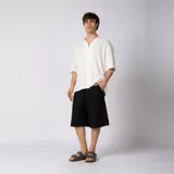 Bermuda sastrera gris de corte baggy, con pinzas al frente y diseño holgado que se extiende por debajo de la rodilla.