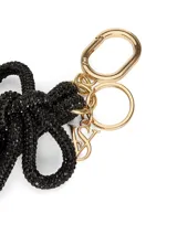 Llavero con correa de muñeca de textura brillante en color negro, adornado con un nudo y herrajes metálicos dorados.