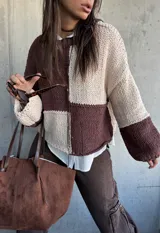 Sweater de punto con diseño de bloques de color en tonos chocolate y beige, de corte holgado y mangas largas con puños ajustados.