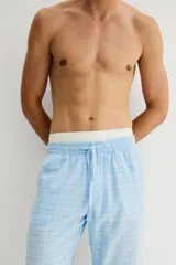 Pantalón de franela de algodón suave, color celeste con estampado a cuadros blancos. Tiene cintura elástica con cordón ajustable y bolsillos al bies. Corte relajado.