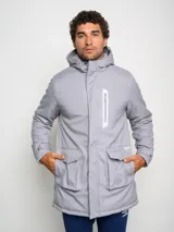 Parka larga gris con capucha, cierre frontal con cremallera y botones a presión, múltiples bolsillos y logo de Umbro en el pecho.