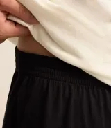 Conjunto de pijama para hombre, compuesto por remera de algodón color crudo con cuello redondo, mangas cortas y estampado de Garfield en un sillón, y short negro de algodón con cintura elástica.