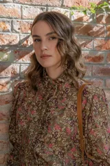 Camisa marrón con estampado floral, cuello alto con volantes y mangas largas abullonadas.