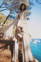 Chaleco largo de tejido de punto color azul verdoso, sin mangas y con flecos en el ruedo. Presenta calados con diseño geométrico.