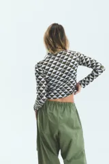 Polera de manga larga con cuello alto, confeccionada en lycra estampada con diseño geométrico de triángulos y monograma exclusivo de la marca.