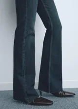 Jeans de tiro medio con corte flare y bajo deshilachado. Presentan diseño de cinco bolsillos, cierre frontal con cremallera y botón, y trabillas para cinturón.