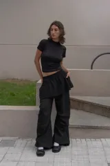 Pantalón negro unisex con pretina elástica, bolsillos laterales y pinzas horizontales en el frente a la altura de las rodillas.