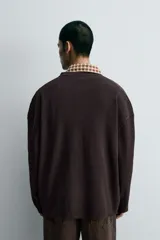 Cárdigan de punto negro con textura de canalé, cuello redondo y cierre frontal de botones.