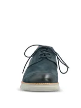 Zapato de estilo derby en color azul marino, confeccionado en cuero con detalles de perforaciones tipo brogue, talón en tono tostado y suela de goma gris claro.