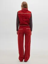 Chaleco de pana color negro con cuello camisero, cierre frontal con botones metálicos dorados, costuras contrastantes en tono claro y pequeño parche distintivo en el pecho.