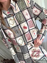 Camisa de algodón con cuello clásico, manga larga con puños abotonados y cierre frontal con botones, con un llamativo estampado de naipes y cartas de juego.