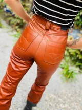 Pantalón de cuero celeste de tiro alto y silueta recta, con bolsillos y cierre frontal.