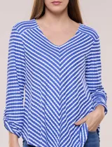 Remera de calce relajado y silueta fluida, con escote en V y mangas tres cuartos con presilla y botón. Diseño de rayas dispuestas en ángulo tipo espiga en el delantero y ruedo redondeado.