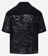 Camisa masculina negra de corte boxy, confeccionada en viscosa texturizada con efecto cutout. Presenta cuello solapa, manga corta y cierre abotonado frontal.