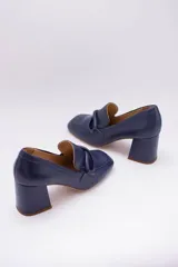 Zapato de cuero rojo con aplique decorativo en el empeine y tacón cuadrado.