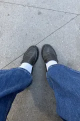 Mocasines de cuero negro con diseño clásico, punta redondeada con costuras fruncidas y tira decorativa en el empeine.
