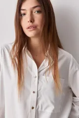 Camisa celeste de calce relajado, con cuello camisero, bolsillo aplicado en el pecho y mangas largas con puños abotonados. Cuenta con lazos ajustables en los laterales para fruncir y regular la silueta.