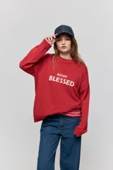 Sweater de punto marrón de tejido liviano y calce relajado, con hombros caídos, cuello redondo y puños y cintura en rib. Cuenta con una estampa tejida en el frente con la frase "Estoy Blessed" en color amarillo.