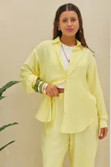 Camisa amarilla de manga larga, con cuello camisero, cierre frontal de botones y corte oversize.