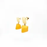 Aros colgantes con forma geométrica, con pieza superior rectangular color crema y pieza inferior cuadrada color ámbar.