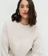Blusa básica de manga larga con cuello redondo y puños ajustados, confeccionada en tejido de algodón y poliéster. Presenta un corte regular anatómico y diseño liso sin estampas.