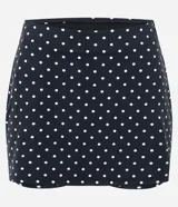 Short pollera deportivo negro con estampa de lunares blancos, confeccionado en microfibra con cintura alta y short interno integrado.