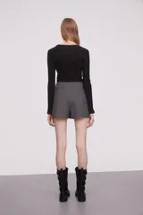 Minifalda gris de corte cruzado con detalle de cinturón lateral en cuero sintético negro con hebilla metálica.