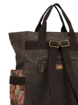 Mochila de diseño patchwork en tonos marrones, confeccionada en una combinación de pana, tela encerada y tejido estampado. Cuenta con un bolsillo frontal con cierre, manijas superiores fijas, correas ajustables y un llavero decorativo con borlas y cuentas colgando de un lateral.