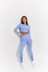 Conjunto deportivo de dos piezas compuesto por un top de manga larga con cuello redondo y calzas de tiro alto. Ambas prendas presentan un diseño seamless con detalles de textura en relieve y un acabado jaspeado en color azul cielo.