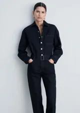 Mono largo de jean azul oscuro, con cuello camisero, mangas largas y cierre frontal con botones a presión. Incluye cinturón con hebilla metálica, cuatro bolsillos y trabillas.