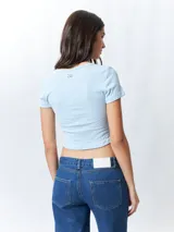 Remera de manga corta color verde lima, ajustada al cuerpo, con un corte cruzado en la parte inferior y un recorte en forma de corazón en el centro del pecho.