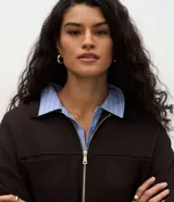Campera tipo parka color verde oscuro, confeccionada en modal con cierre frontal metálico, cuello camisero, bolsillos frontales y cordón ajustable en la cintura.