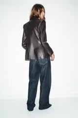 Blazer de corte cruzado confeccionada en material efecto piel, con cuello solapa, manga larga con hombreras, bolsillos delanteros con solapa y cierre frontal con botones.
