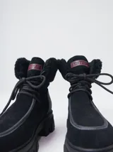 Borcegos de caña baja con diseño robusto, confeccionados en una combinación de gamuza y cuero sintético en tonos verde oliva. Presentan suela track de goma dentada en color suela, cordones al tono con ojalillos amarillos y cuello acolchado para mayor confort.