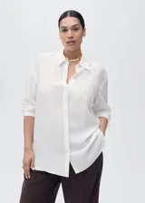 Camisa de lyocell color blanco, con cuello camisero, manga larga con puños abotonados, diseño recto y cierre frontal con botones ocultos.