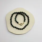 Collar de cuentas esféricas de piedra natural ágata musgo de 8 mm, con nudos de hilo verde entre cada cuenta y cierre frontal tipo mosquetón circular con baño de oro.