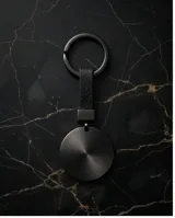 Llavero de diseño minimalista con dije circular de metal en acabado negro mate y argolla metálica a juego.
