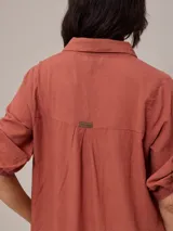 Vestido camisero largo de corte holgado, con cuello clásico, cierre frontal completo con botones y mangas tres cuartos.