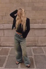 Jeans de tiro medio y corte ancho, confeccionados en denim con lavado estilo vintage de efecto desgastado. Presentan diseño de doble cinturilla superpuesta, cinco bolsillos tradicionales, trabillas para cinto y cierre frontal con cremallera y botón metálico.