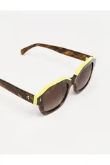 Lentes de sol Tiwi modelo Carole, con montura gruesa de acetato color marrón con efecto madera y borde superior amarillo. Lentes degradados marrones.