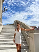 Minivestido blanco con cuello halter y cierre metálico frontal.