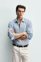 Camisa celeste de lino de corte regular fit, con cuello abotonado, manga larga y cierre frontal de botonadura.