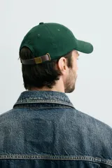Gorra de seis paneles confeccionada en tejido de algodón, color verde oscuro, con parche frontal de letra P en color crema y ajuste posterior.
