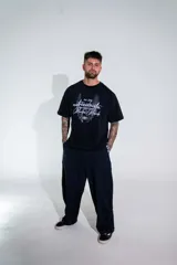 Remera de corte boxy color negro, con mangas cortas y estampa frontal con tipografía manuscrita y diseño gráfico.