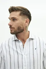 Camisa de manga larga de lino y algodón, color blanco con rayas verticales en tonos gris y beige. Presenta un corte semi slim y un pequeño logo bordado en el pecho.
