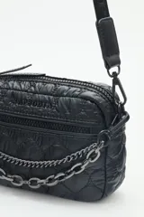 Bandolera pequeña de nylon acolchado con patrón de corazones, color rojo brillante. Posee correa regulable, cierre principal y bolsillo frontal con cierre. Incluye un llavero colgante con dije de corazón.