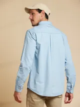 Camisa celeste de manga larga con cuello abotonado y bolsillo en el pecho.
